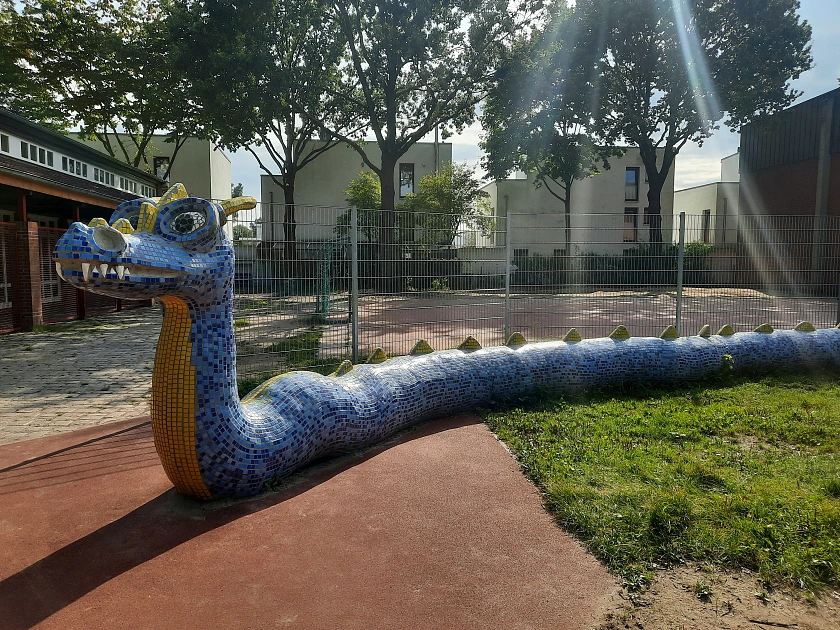 Auf diesem Bild ist ein Kunstwerk in Form eines Drachen zu sehen, der auf dem Schulhof zu finden ist.